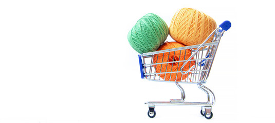 Wall Mural - Trolley with yarn for knitting. Yarn for crocheting. Design of the embroidery section. Needlework. Hobbies and recreation. Colored threads on a white background. Copy space