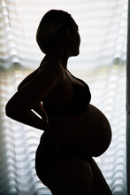 Silhouette Of Pregnant Black Woman In Third Trimester In Front Of Window