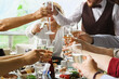 glasses of champagne in hand over a table with food at shallow depth of field