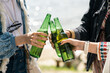 © pressmaster - Close-up of unrecognizable girls standing in circle and clinking beer bottles outdoors