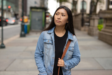 Poster - Young Asian woman walking city street serious face