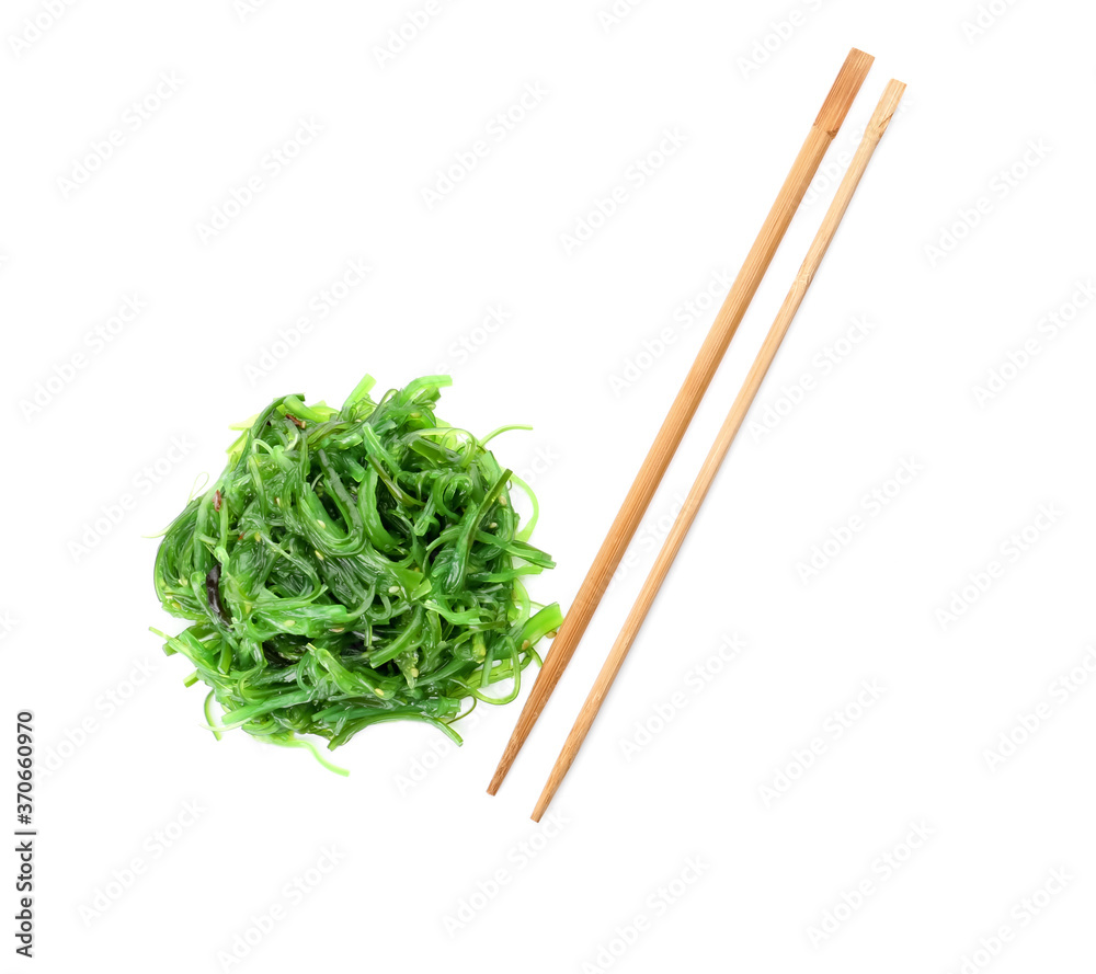 Chopsticks with tasty seaweed salad on white background
