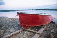 Old Red Rowboat Lying At Shore In The Evening.