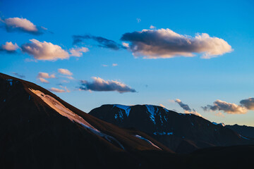 Wall Mural - atmospheric dawn landscape with silhouettes of snowy mountains with glaciers. sunset sky with golden
