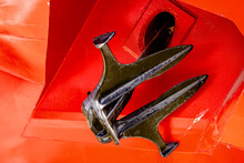 Close-up Of Black Metal Anchor Of Merchant Ship On Red Background. High Quality Photo