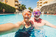 Funny couple of mature people take selfie picutre while enojy and have fun at the pool in residence - elderly retired happy lifestyle with aged couple in summer leisure activity together