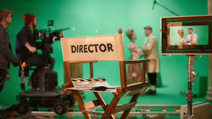 Wall Mural - On Film Studio Set Focus on Empty Director's Chair. In the Background Professional Crew Shooting Historic Movie, Cameraman on Railway Trolley Shooting Green Screen Scene with Actors for History Movie