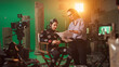 © Gorodenkoff - On Film Set: Prominent Female Director Explains Scene to Male Actor Wearing Motion Capture Suit and Playing Green Screen Scene in Superhero Movie. On Big Film Studio Professional Crew