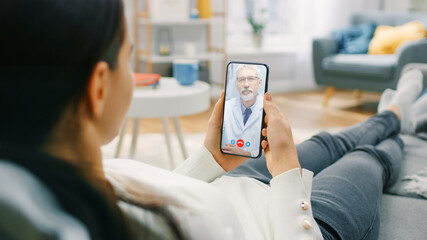 Young Girl Sick at Home Using Smartphone to Talk to Her Doctor via Video Conference Medical App. Woman Checks Possible Symptoms with Professional Physician, Using Online Video Chat Application