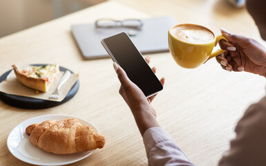 Poster - Unrecognizable black woman using smartphone while having breakfast with coffee at cafe, space for design on screen