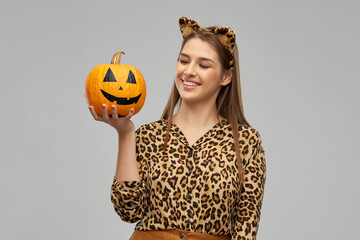 Sticker - holiday, theme party and people concept - happy smiling woman in halloween costume of leopard with ears holding jack-o-lantern pumpkin over grey background