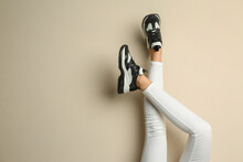 Woman Wearing Sneakers On Beige Background, Closeup. Space For Text