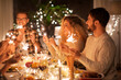 © Syda Productions - holidays, celebration and people concept - happy friends with sparklers having christmas dinner at home