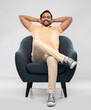 © Syda Productions - people and furniture concept - happy smiling young indian man sitting in chair over grey background