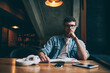 © BullRun - Portrait of confused hipster guy sitting at desktop spending time for autodidact and looking at camera, concentrated puzzled man in eyeglasses preparing for exam and doing school homework indoors