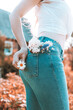 Flowers in the back pocket of blue jeans, a girl with a camomile