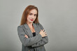 © Petro - Standing and cross her arms on chest. Young attractive woman, dressed gray jacket, with green eyes, light brown hair, background