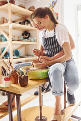 With her boyfriend or husband. Young female ceramist have a works indoors with handmade clay product. Conception of pottery