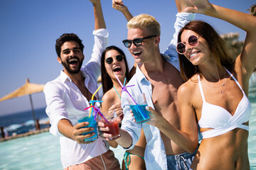 Group of happy friends having fun dancing at swimming pool outdoors