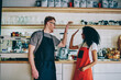 © BullRun - Cheerful caucasian barista giving five african american waitress for great job during teamwork in own cafeteria.Positive diverse male and female employees in aprons collaborating on successful startup