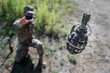 Grenade in flight with safety pin. A soldier in a mask threw a grenade, top view, focus on the grenade. F1 grenade in flight.
