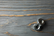 Metal Nuts On Gray Wooden Background, Space For Text