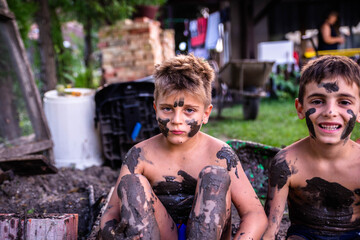 Lovely guys in the mud. The children are playing in the yard, they are dirty with mud, but they are very happy