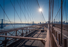 Cars Driving On Famous Brooklyn Bridge Over River In Sunny Afternoon In New York City