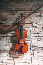 Unrecognizable Ethnic Male Violinist With Shiny Violin And Bow On Background Of Stone Wall In Modern Apartment