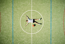 From Above Drone View Of Relaxed Female Basketball Player With Ball Lying On Center Circle Of Court While Resting After Training