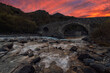 © Juan Lopez/ADDICTIVE STOCK - River and stony shore streaming through rocks and ancient stone bridge at sunset