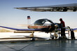© Kavi Sanchez/ADDICTIVE STOCK - Side view of male employee in uniform cleaning jet airplane while standing on airfield during sunny day