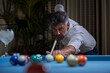 © Philippe Degroote/ADDICTIVE STOCK - Confident focused gray haired male in white shirt preparing for shot with cue while playing billiards game