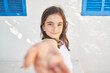© Philippe Degroote/ADDICTIVE STOCK - Adorable preteen girl outstretching hand forward camera and smiling while standing against white wall of country house in summer day