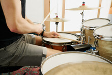 Cropped Unrecognizable Casual Male Drummer Playing On Drum Kit Sitting On White Background Stage