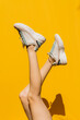© Westend61 - Woman's legs in sports shoes over yellow wall during sunny day