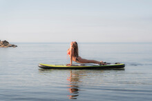 Woman Practicing Upward Facing Dog Position On Paddleboard Over Sea Against Sky