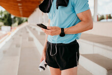 Male Athlete Checking Smartphone On Grandstand In Stadium