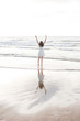 © Westend61 - Carefree young woman with arms raised standing at shore against clear sky