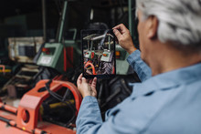 Senior Man Taking Picture Of A Tractor In Barn With A Tablet