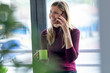 © Westend61 - Smiling female entrepreneur talking over smart phone while sitting against window in office