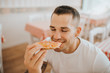 © Westend61 - Close-up of young man with eyes closed eating pizza while sitting in restaurant