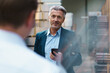© Westend61 - Businessman holding mobile phone looking at colleague in a factory