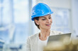 © Westend61 - Mature female manager in blue hardhat reading clipboard at factory