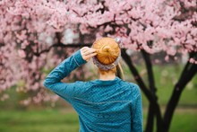 Back View Of Redhead Woman Standing In Front Of Cherry Blossom Tree
