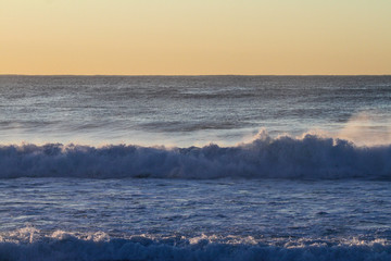 Wall Mural - sunrise over the ocean with waves crashing onto the beach, room for text