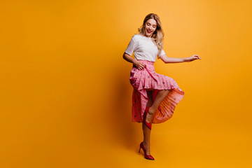 Poster - Full-length shot of lovely slim girl in long skirt. Fascinating woman dancing on yellow background.