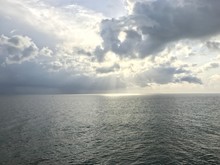 View Of The Atlantic Ocean With The  Sun Peeking Through The Clouds.