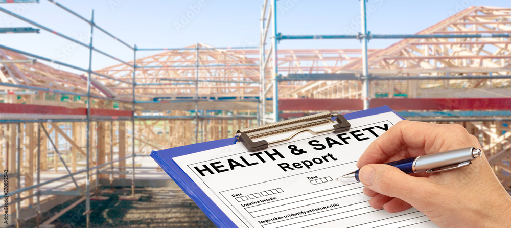 Health and Safety Report Banner hand with clipboard beside new build construction - obrazy, fototapety, plakaty 
