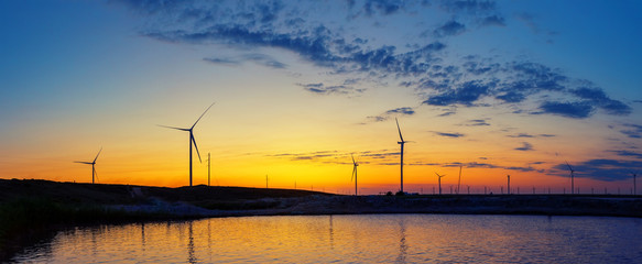 Wall Mural - wind generators power plant on lake at sunset